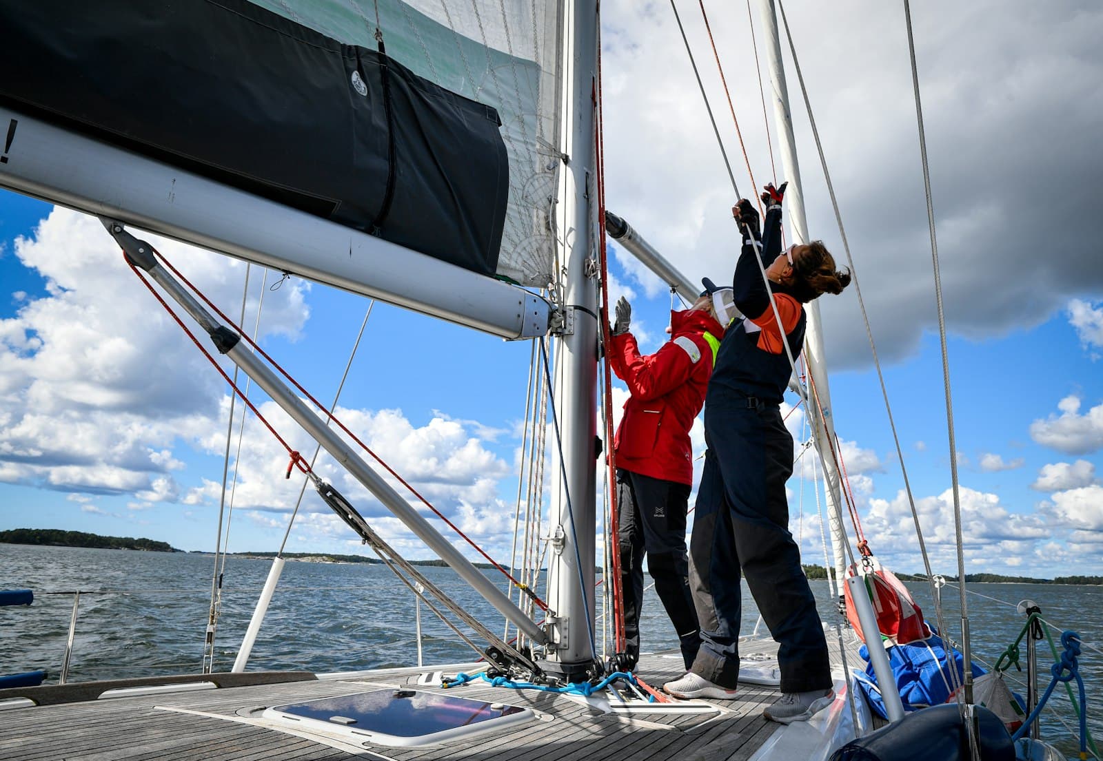 Crew adjusting sails on a sailboat deck