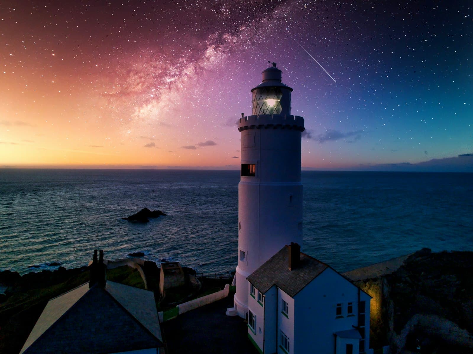 Phare illuminé au bord de la mer de nuit